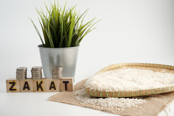 ZAKAT WORD coin stacked and rice on white background. Zakat for moslem concept.