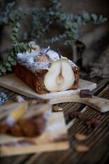 Chocolate cake with pears and chocolate with icing sugar on a wooden table