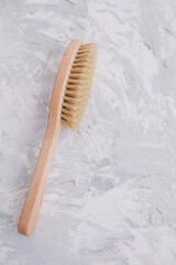 Brush for body on a textured gray background. Spa beauty products. Natural material. Massaging salon concept. Flat lay, copy space, top view. Concept skincare organic wooden body skin massage brush.  