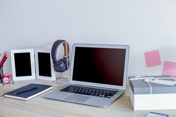 Laptop on the table with headphone and stionary items on table. 