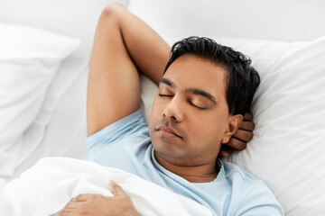 Fototapeta na wymiar people, bedtime and rest concept - indian man sleeping in bed at home