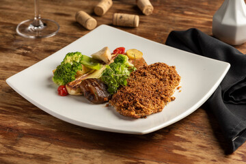 fish baked with crust and vegetables on white plate on a wooden table