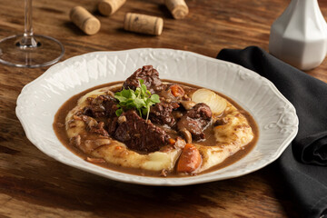 italian ossobuco steak with bone slow cooked with gravy and mashed potatoes on a white plate