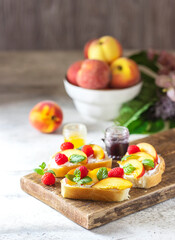 Summer snack - sandwiches with cream cheese and fresh peaches on a light concrete background. Homemade Summer Breakfast.