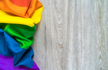 The symbol of the LGBT community is a gay pride rainbow on a wooden background.