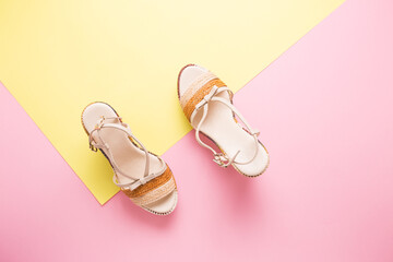 Female summer sandals on a yellow-pink background close-up.