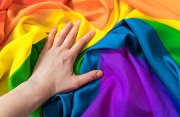 Gay pride rainbow. Close-up of a hand on a rainbow flag symbol of the LGBT community. 