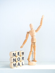 New Normal, words on wooden alphabet cube and wooden figure.