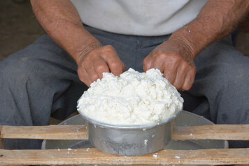 Front view of hands of the shepherd pressing the curd