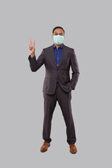 Businessman Showing Peace Sign Wearing Medical Mask. Indian Businessman Standing Full Length.