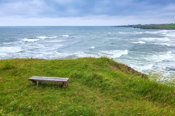 Panoramic spring view with an alone wooden bench at a green wild beach, the Black Sea coast, Bulgaria.