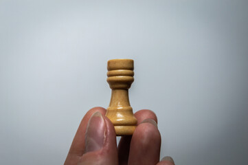 The hand holds a chess piece. Chess rook on a white background