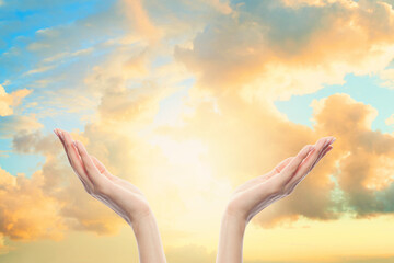 Woman hands reach for the sky clouds in prayer