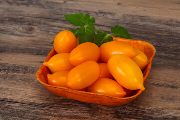 Yellow tomato heap in the wooden bowl