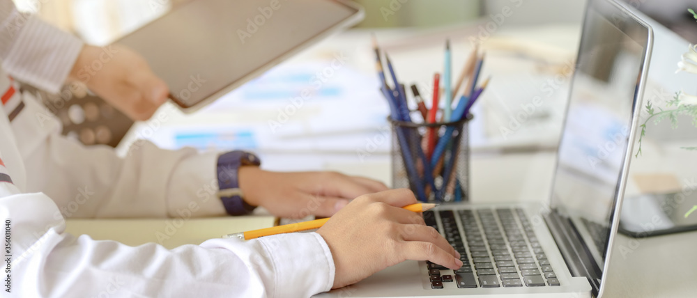 Poster side view of ui developer working on laptop with stationery and paperwork