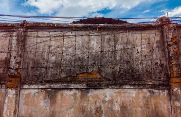 Barbed wire on background of old dirty concrete painted cracked wall. Copy space ideal for use in the design or wallpaper