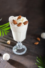 Healthy vegan smoothie with banana and coconut milk on dark background. Summer Tropical cocktail recipe. Close up.