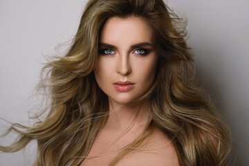 Fototapeta premium Gorgeous woman with a beautiful curly hair and professional makeup