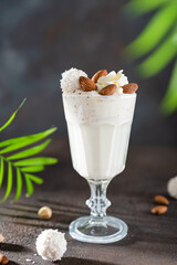 Healthy vegan smoothie with banana and coconut milk on dark background. Tropical cocktail recipe. Close up. Summer party
