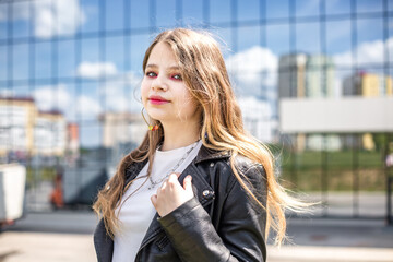 Fototapeta premium young schoolgirl in black leather jacket with bright pink make-up posing in the parking lot