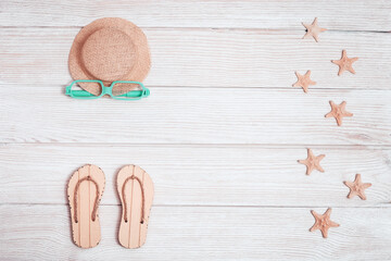 Things for summer vacation by sea, summer shoes - flip-flops,  starfish, sunglasses, yellow hat from sun on white wooden background with copy space. Summer flat lay.