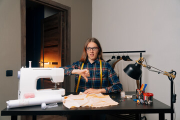fashion designer sitting at the workplace at the sewing machine. bad work during coronavirus
