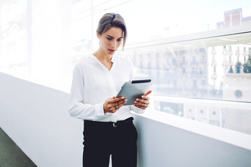 Woman entrepreneur concentrated reading electronic book on touch pad during work break