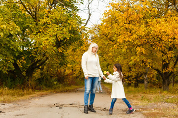 Mother and daughter walking in the autumn forest