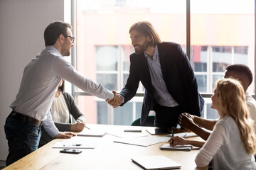 Negotiation starts with businessmen leaders of business parties shake hands, boss greeting company client diverse businesspeople gathered together in modern boardroom, solve issues partnership concept