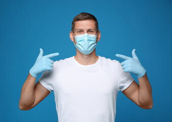 Male volunteer in mask and gloves on blue background. Protective measures during coronavirus...
