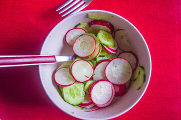 Radish and zucchini salad, with oil, salt and pepper on scarlet red tablecloth