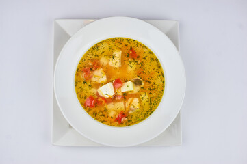 soup with potatoes, cheese, tomatoes and greens on a white background