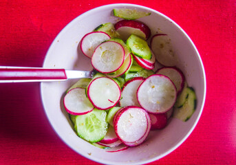 Radish and zucchini salad, with oil, salt and pepper on scarlet red tablecloth