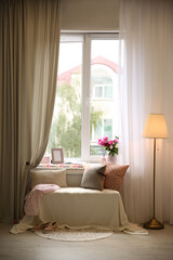 Comfortable place for rest with cushions and peony flowers near window indoors