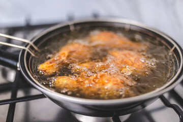 Frying Chicken in a pan full of oil. A pan with a frying basket. Concept of preparing Fried ORGANIC CHICKEN DRUMSTICK on the gas stove.