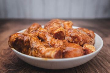 Close-up of a bowl full of marinated FRESH RAW ORGANIC CHICKEN DRUMSTICK with lots of spices on a dark brown wooden table.