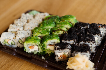 Sushi Roll Delivery. Salmon, eel, tuna, avocado, royal prawn, cream cheese Philadelphia, caviar tobica, chuka, sea cabbage shrimps on wood background