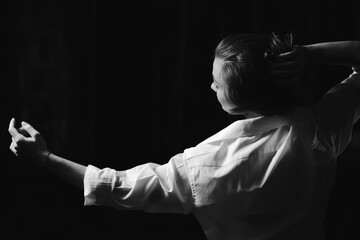 Black and white portrait of beautiful dancing caucasian girl with dramatical emotion on the stage.Retro fashion. Black and white image.
