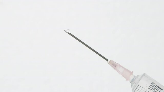 Drops of water with medical equipment syringe needle on white background. Selective focus.