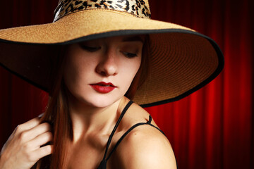 Portrait of a beautiful woman with red lips in hat isolated at red curtain with copy space.Headshot with different emotions.