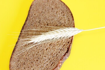 A piece of rye claid and rye ear laid on a yellow background