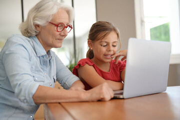 Grandmother with little girl using laptop at home