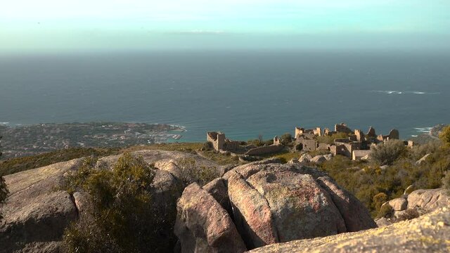 A static shot in Corsica of the abandoned village of Occi. The strong breeze moves the bushes, the sea stretches out into the horizon. 
