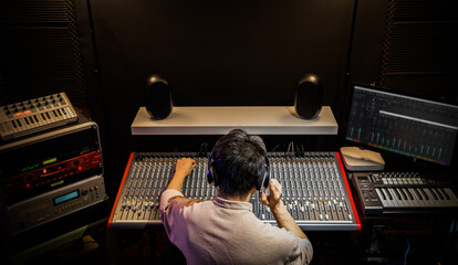 back of asian producer, dj, sound engineer mixing music in recording, broadcasting studio
