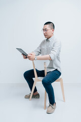 Young male in gray shirt sits on a chair and looks at a tablet