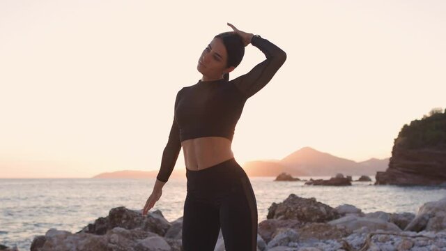 sexy athletic woman stretching exercises on beach at sunset. Sporty attractive woman working out and stretching on beach at sunset. Female fitness model in athletic wear. Healthy lifestyle motivation.