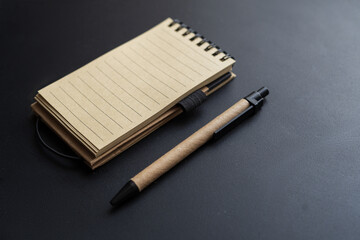 Yellow-black notebook and pen on the black table. Copy space. 