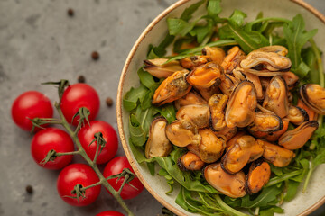 mussel meat on a plate with arugula and cherry tomatoes