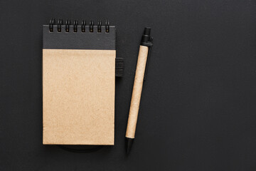 Yellow-black notebook and pen on the black table. Copy space. 