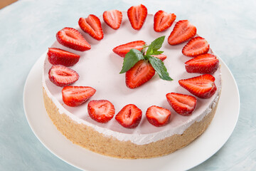 Sweet breakfast, delicious cheesecake with fresh strawberries and mint, homemade recipe without baking, on a blue stone table. Copy space.